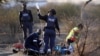 A paramedic (front L) receives help from a policewomen as he tends to the injured after protesting miners were shot outside a South African mine in Rustenburg, August 16, 2012. 