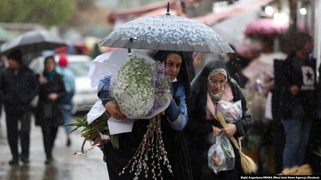 Iranian women walk through rain in a flower market, ahead of Nowruz, the Iranian New Year, in Tehran, March 16, 2023. 