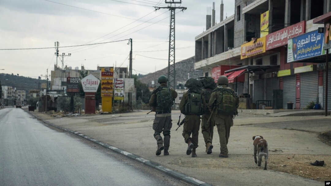 FILE — Israeli soldiers patrol the Palestinian town of Hawara, which emptied after the Israeli military closed shops and banned Palestinian vehicles from the main road in the wake of Palestinian militant attacks and settler violence, Nov. 12, 2023.