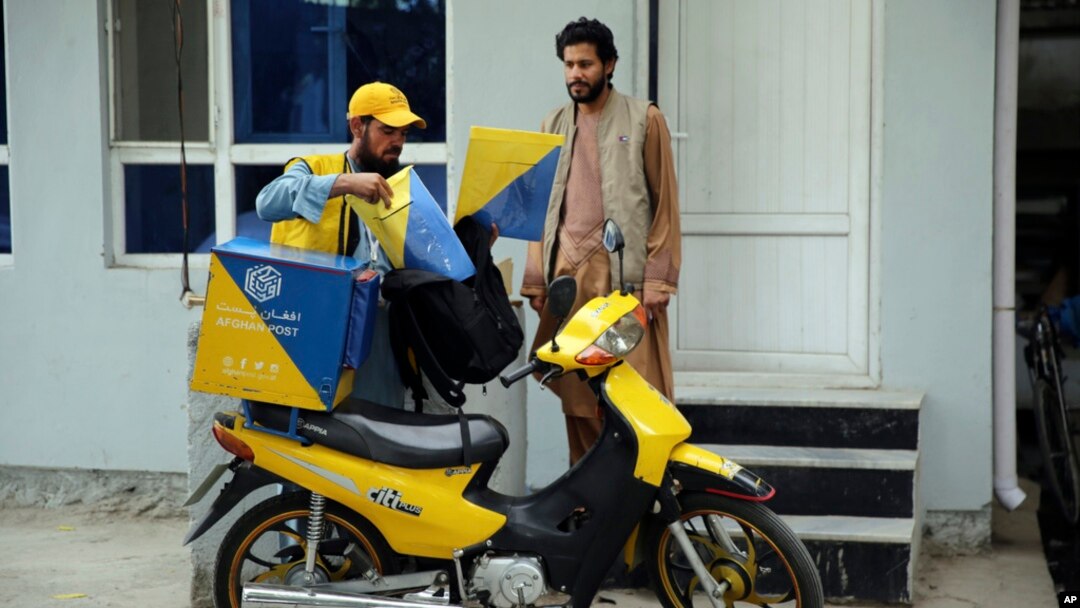 A postman delivers to a man in front of his house in the city of Kabul, Afghanistan, July 3, 2024.