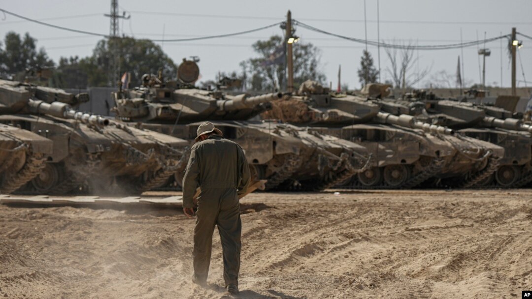 Israeli soldiers work on tanks at a staging ground near the border with the Gaza Strip, in southern Israel, April 11, 2024.
