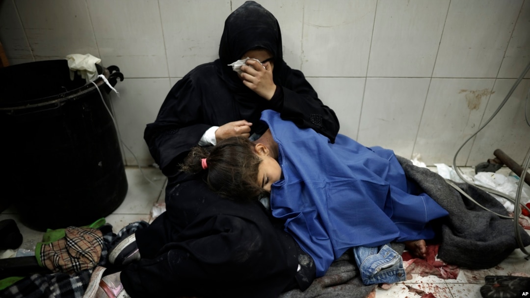 A Palestinian woman cries as she sits next to her girl wounded in the Israeli bombardment of the Gaza Strip while receiving treatment at the Nasser hospital in Khan Younis, Southern Gaza Strip, Jan. 22, 2024. 