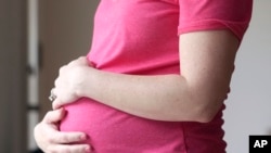 FILE - A pregnant woman stands for a portrait in Dallas, Texas, May 18, 2023. A Chinese woman's account of how she was lured into China's illegal surrogacy industry before suffering a miscarriage went viral on Chinese social media this week.