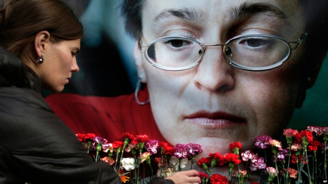FILE - A woman places flowers before a portrait of slain Russian journalist Anna Politkovskaya in Moscow on Oct. 7, 2009.