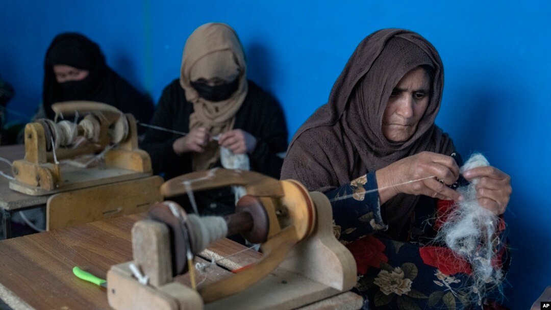Women weave wool for traditional Afghan carpets at a factory in Kabul, Afghanistan, March 6, 2023.