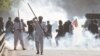 Supporters of former Prime Minister Imran Khan react amid tear gas smoke fired by the police to disperse them during clashes, in Lahore, Pakistan, March 8, 2023.