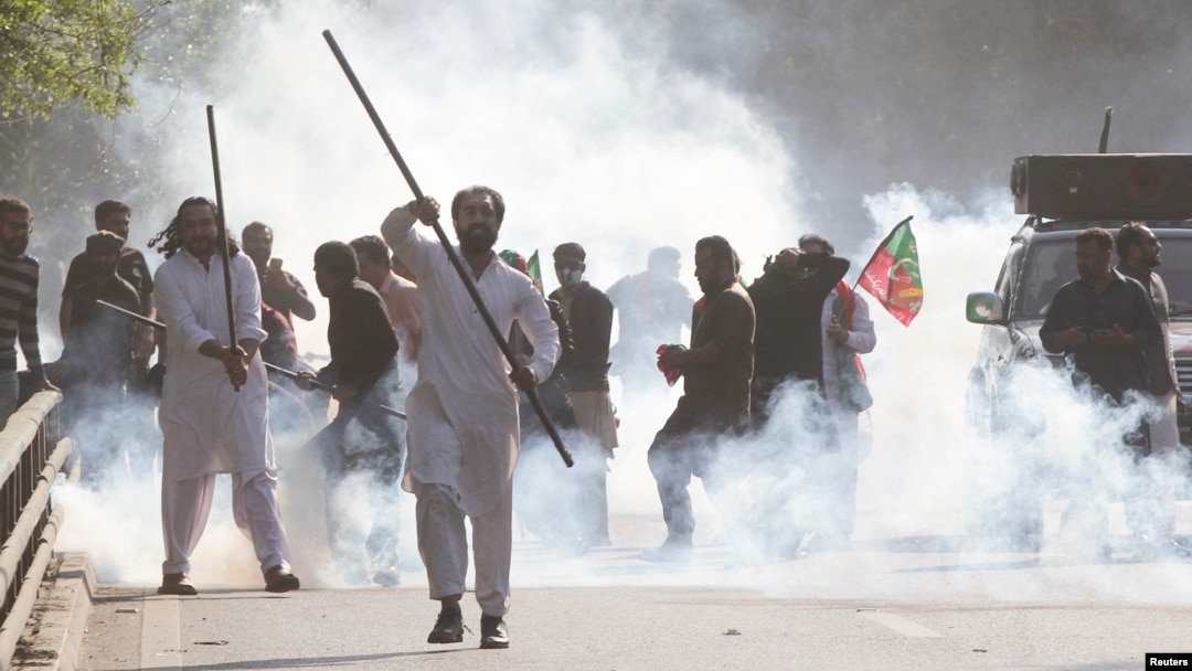 Supporters of former Prime Minister Imran Khan react amid tear gas smoke fired by the police to disperse them during clashes, in Lahore, Pakistan, March 8, 2023.