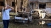 A man stands next to burnt-out cars in the courtyard of a multi-story residential building, which according to local authorities was hit by debris from a destroyed Ukrainian missile, in Kursk, Russia Aug. 11, 2024.