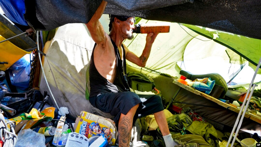FILE - Charles Sanders, 59, sits in his tent inside a homeless encampment called 'The Zone,' July 14, 2023, in downtown Phoenix.