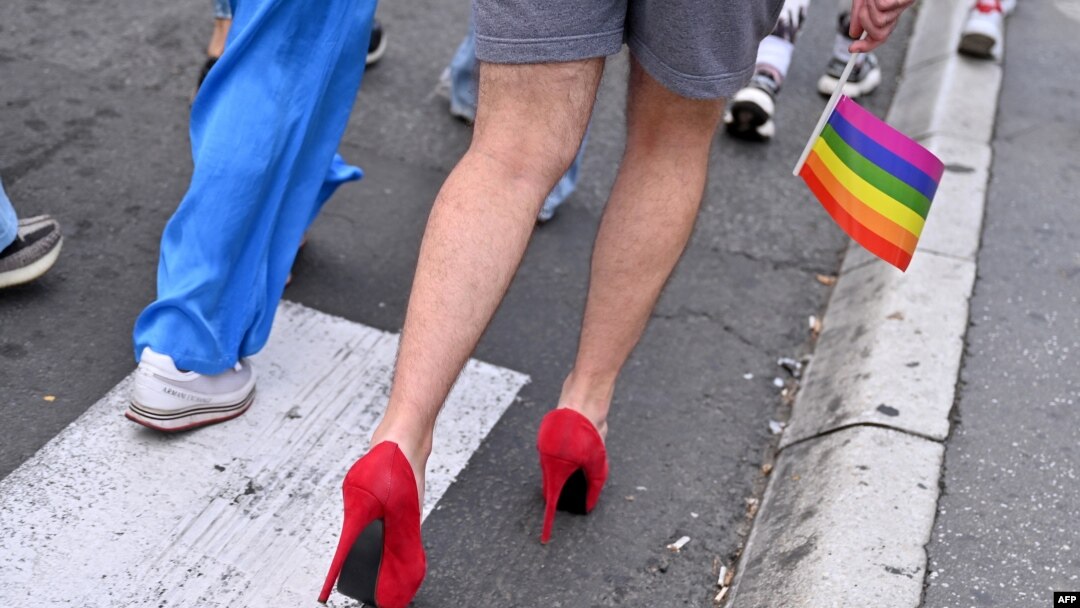 FILE - A participant holding a gay pride flag walks in high heels during a pride march, in Belgrade, Serbia, September 18, 2021. 