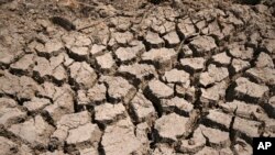 FILE - Cracked dry mud is seen in a community reservoir that ran nearly empty in southwestern China's Chongqing Municipality, Aug. 20, 2022.