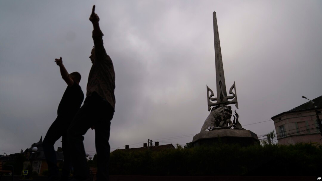 A statue honoring those who fought for Ukraine's freedom stands in Mostyska, western Ukraine, as organizers set up for an event marking the country's Independence Day, Aug. 24, 2022.
