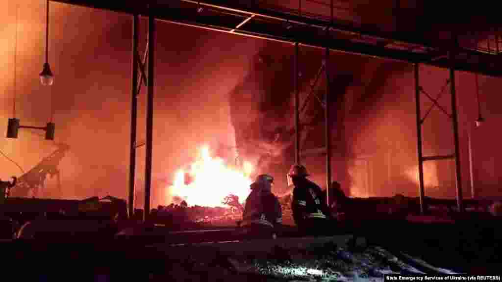 Fire fighters extinguish fire in an oil depot that Ukraine's State Emergency Services say was caused by Russian strikes in Zhytomyr region, March 7, 2022 in this still image obtained from a handout video.