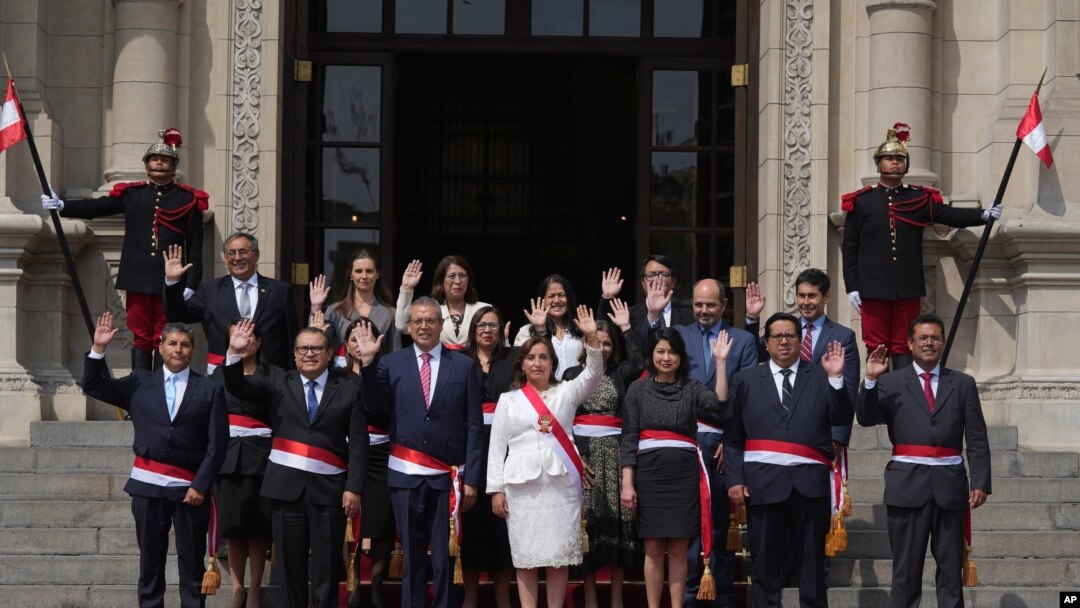 Peruvian President Dina Boluarte, center front, and newly named cabinet members wave as after their swearing-in ceremony on the steps of the government palace in Lima, Peru, Dec. 10, 2022. Boluarte asked each minister to pledge to work "without committing acts of corruption." 