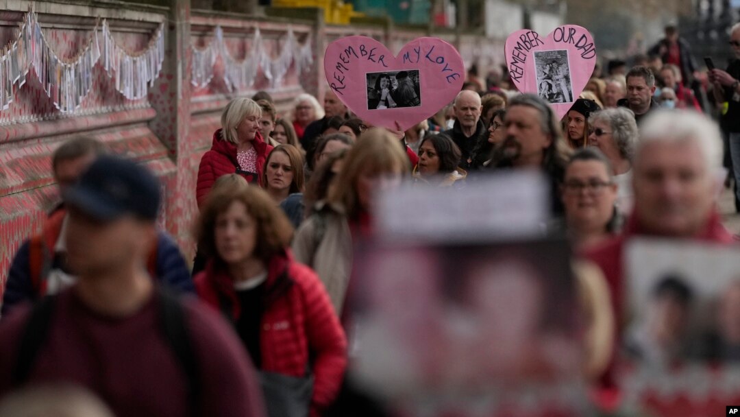 FILE: Family members of those who died of COVID walk past the National Covid Memorial wall in London, March 29, 2022.