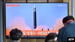 People watch a television screen showing a news broadcast with file footage of a North Korean missile test, at a railway station in Seoul on May 4, 2022. - North Korea fired a ballistic missile on May 4, South Korea's military said, just a week after lead
