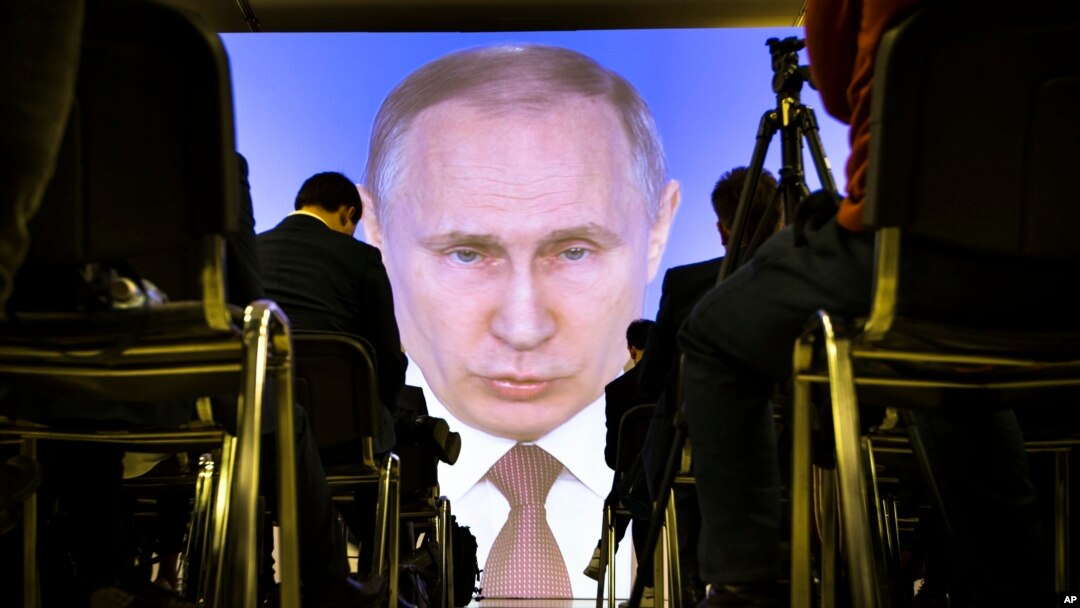FILE - Journalists watch as Russian President Vladimir Putin gives his annual state of the nation address in Manezh in Moscow, Russia, March 1, 2018. 