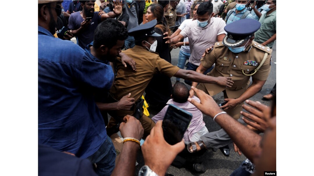 Police officers try to protect a supporter of Sri Lanka's ruling party during a clash with anti-government demonstrators, in front of the Prime Minister's official residence, amid the country's economic crisis, in Colombo, Sri Lanka, May 9, 2022.