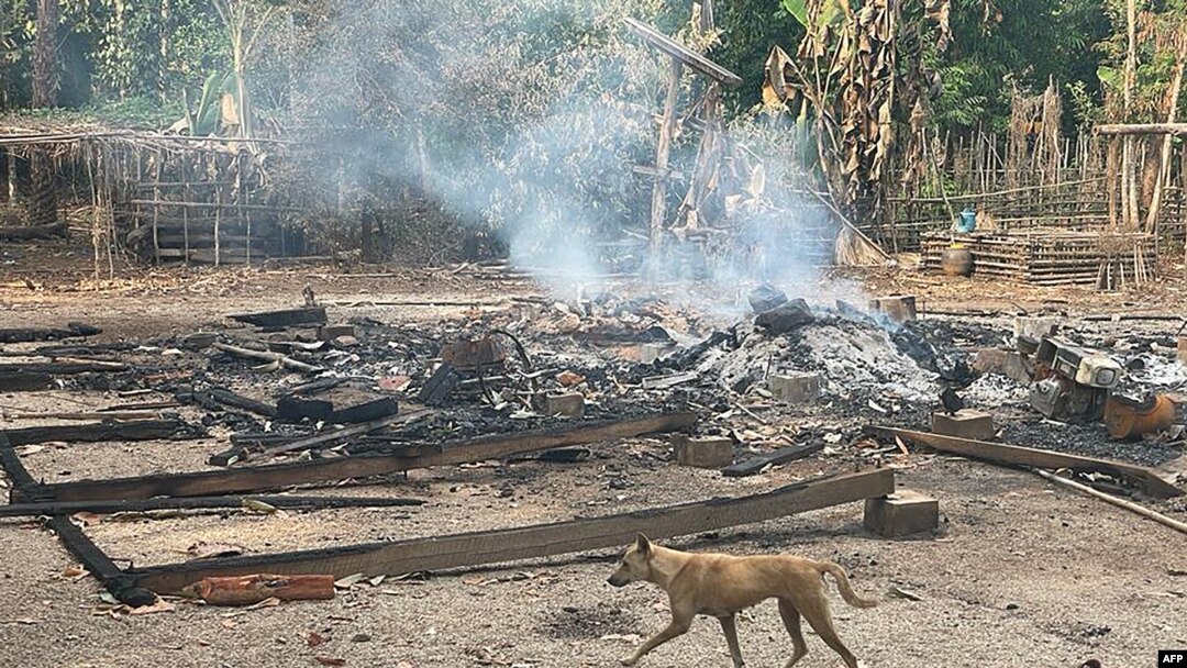 This photo from humanitarian group Free Burma Rangers taken May 3, 2022, and released May 4 shows a dog running past the burning remains of a building after airstrikes and mortar attacks by the Myanmar military, according to the Free Burma Rangers.