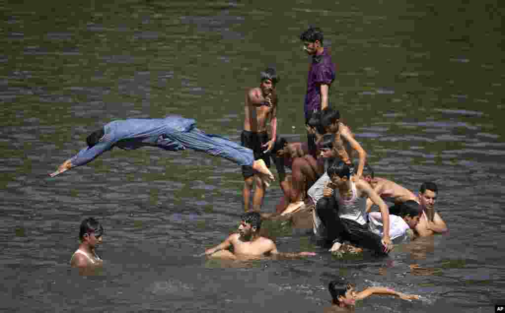 People cool themselves in a stream to beat the heat as temperatures reached 38° C (100° F) during the Muslim holy fasting month of Ramadan in Islamabad, Pakistan