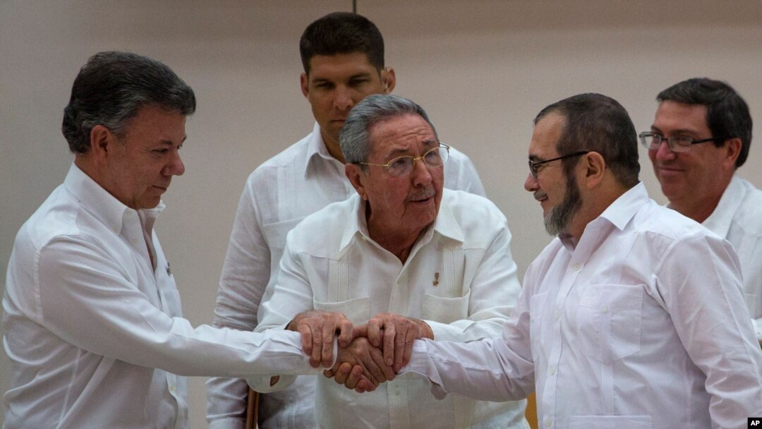 Cuba's President Raul Castro, center, encourages Colombian President Juan Manuel Santos, left, and Commander the Revolutionary Armed Forces of Colombia or FARC, Timoleon Jimenez, known as "Timochenko," to shake hands, in Havana, Cuba, Sept. 23, 2015. 