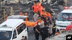 Police officers and first responders carry a body at the site of an explosion at a fireworks factory in Tangerang, on the outskirts of Jakarta, Indonesia, Oct. 26, 2017.