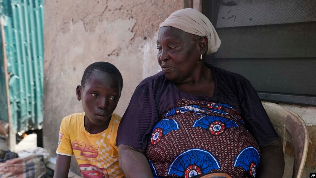 FILE - Funmilayo Kotun, a 66-year-old malaria patient, sits with her grandson Ayomide Kotun outside her house in the Makoko neighborhood of Lagos, Nigeria, on April 20, 2024.
