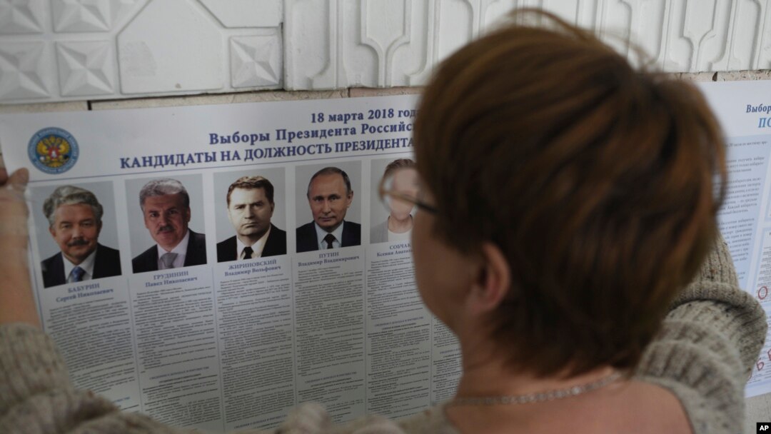 A polling station official hangs a list of candidates for the 2018 Russian presidential election, during preparations at a polling station in Simferopol, Crimea, March 17, 2018. Russian voters, observers and eight presidential candidates are gearing up for an election that will undoubtedly hand Vladimir Putin another six-year term.