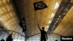 FILE - Anti-extradition bill protesters wave flags with Chinese calligraphy that reads "Liberate Hong Kong, the revolution of our times," at a mass demonstration, in Hong Kong, China, Aug. 12, 2019.