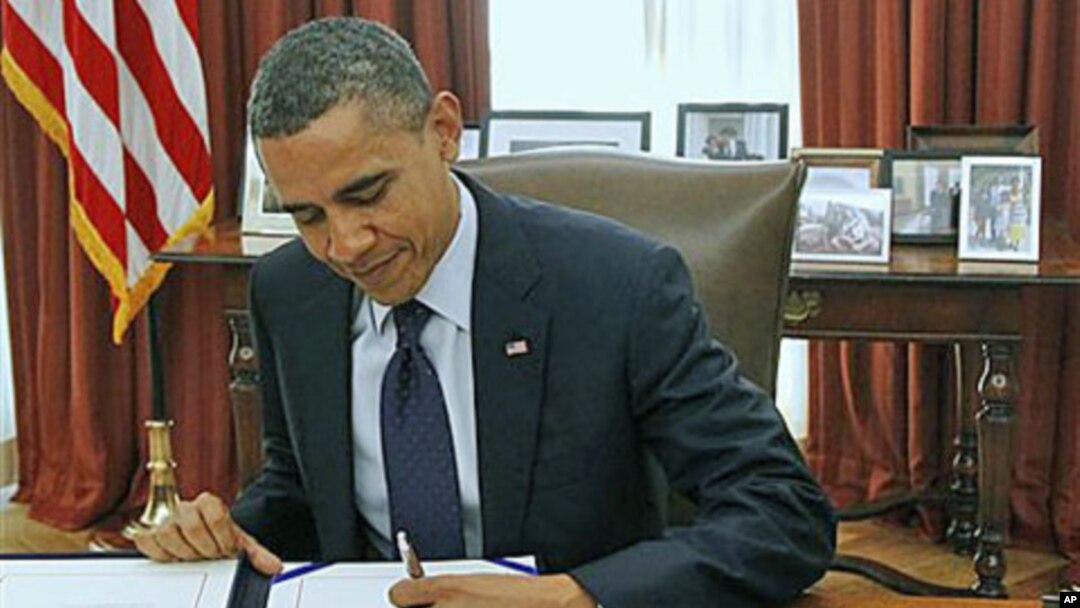 President Barack Obama signs the payroll tax cut extension in the White House Oval Office, in Washington, December 23, 2011.