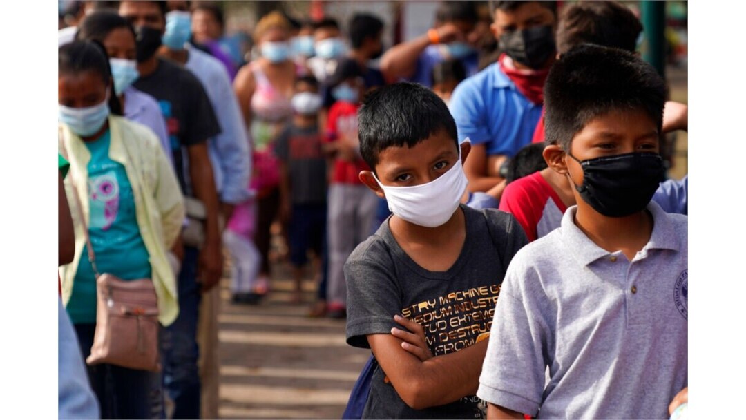 FILE - Children and adults wait in lines for donated food at a makeshift camp for migrants near the U.S.-Mexico border, May 14, 2021, in Reynosa, Mexico.