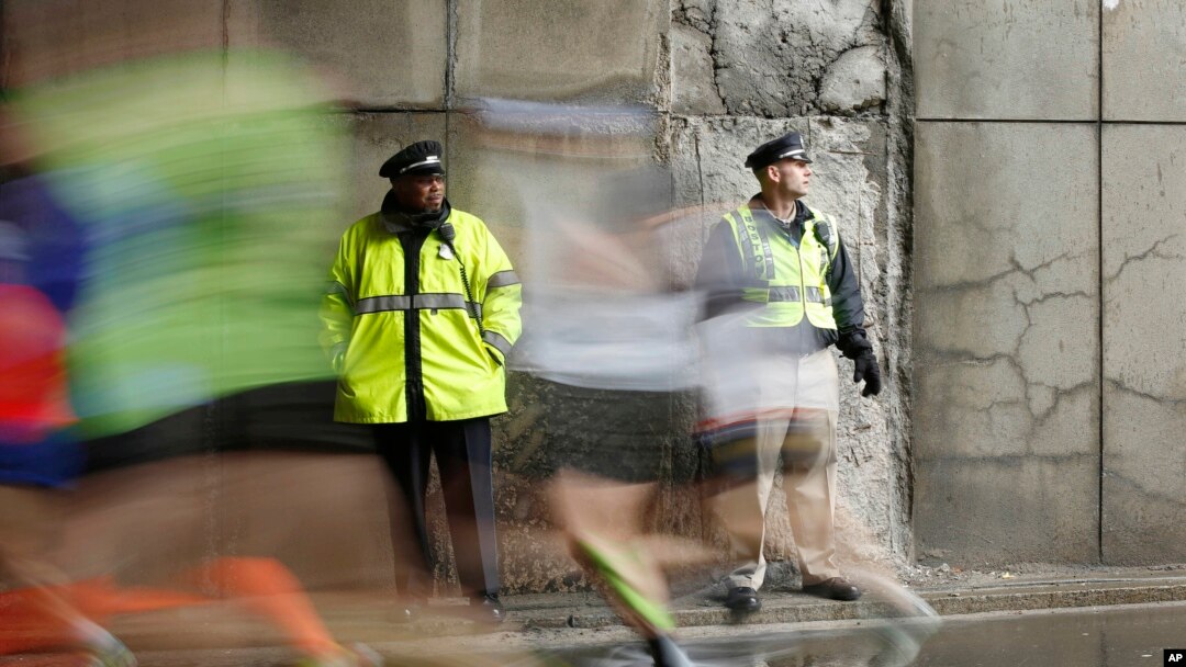 FILE - Police officers stand watch as Boston Marathon participants race along the course in Boston, April 20, 2015.