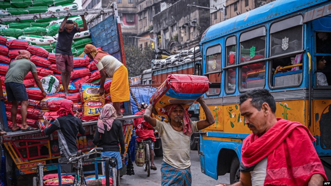 Laborers unload sealed sacks of spices at a wholesale market in Kolkata on Feb. 1, 2023.