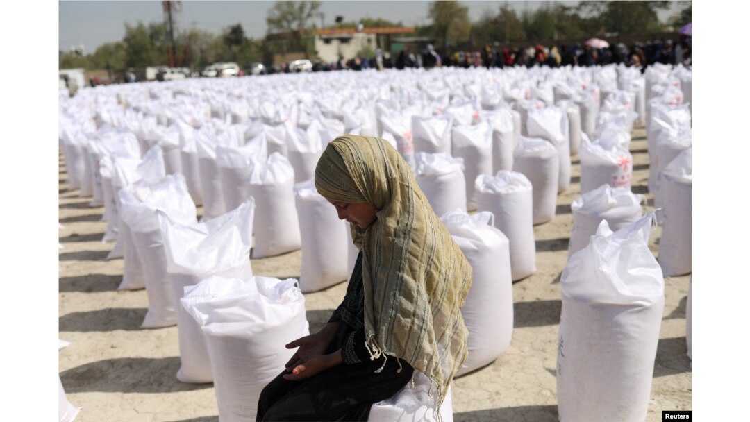 FILE - An Afghan girl waits to receive a rice sack at a distribution center in Kabul, Afghanistan, April 7, 2022.