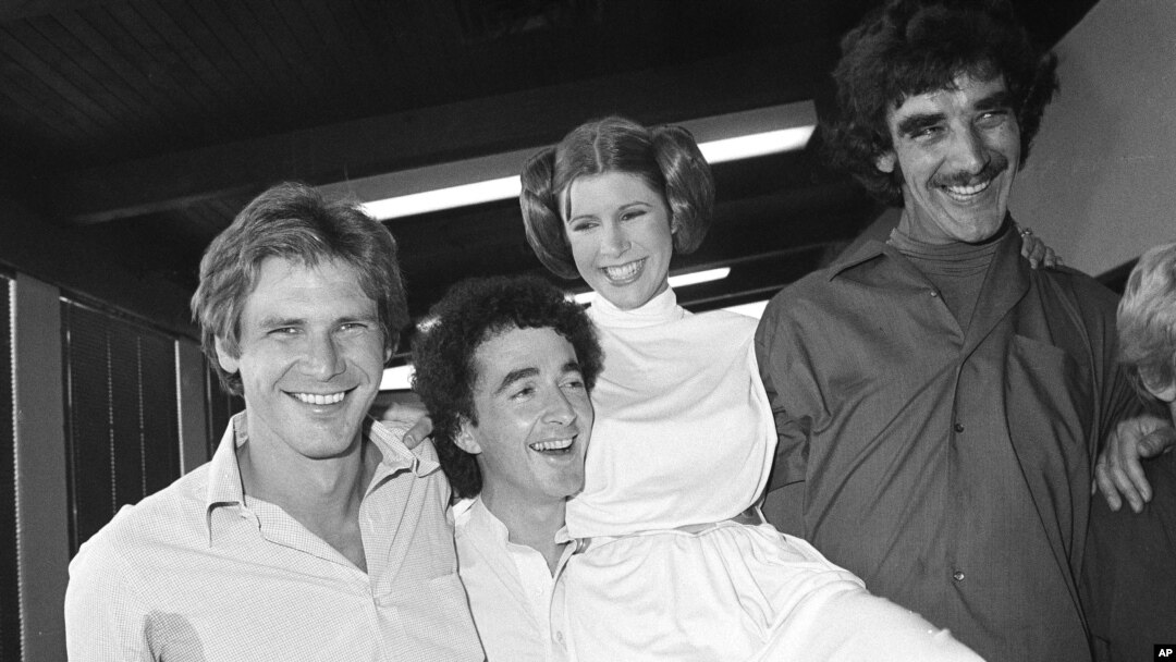 FILE - From left, actors Harrison Ford, Anthony Daniels, Carrie Fisher and Peter Mayhew take a break on the set of a 1978 television special.
