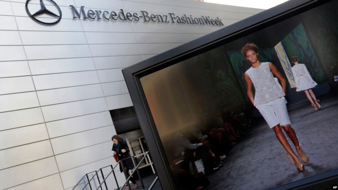 A designer's runway show is shown on a television screen outside the Fashion Week venue at New York's Lincoln Center, Feb. 6, 2013.