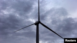 FILE - A worker stands atop a wind turbine during a routine inspection at the Infigen Energy wind farm located on the hills surrounding Lake George, 50 km north of the Australian capital city of Canberra, May 13, 2013.