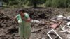 A woman reacts next to a crater caused by Russian bombardments outside her house in the town of Toretske, in Ukraine's Donetsk region, July 17, 2022.