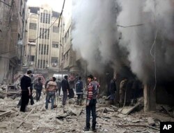 FILE - This photo released Dec 13, 2015, by the Douma Revolution News Network on its Facebook page shows Syrians trying to extinguish fire that was caused by Syrian government aerial bombardment on the Damascus suburb of Douma, Syria.
