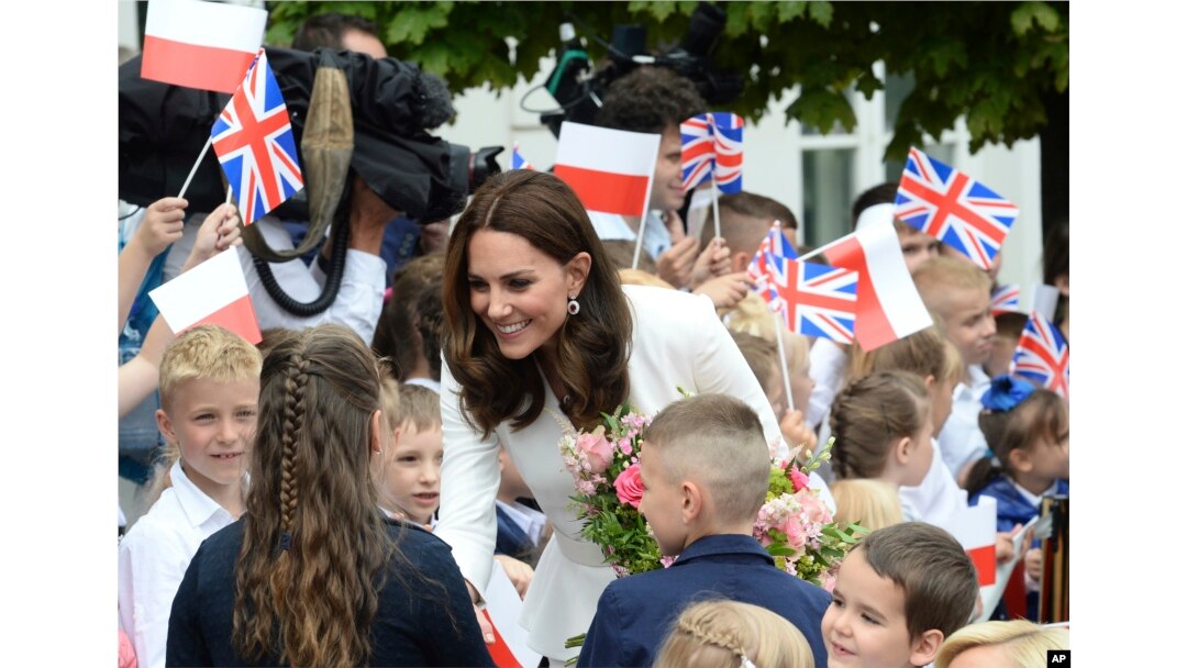 Children welcome Britain's Kate, the Duchess of Cambridge, during her visit with Prince William in front of the presidential palace, in Warsaw, Poland.