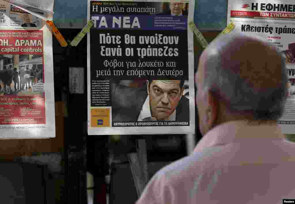 A man reads the front pages of various newspaper hanging at a kiosk in Athens, June 29, 2015.