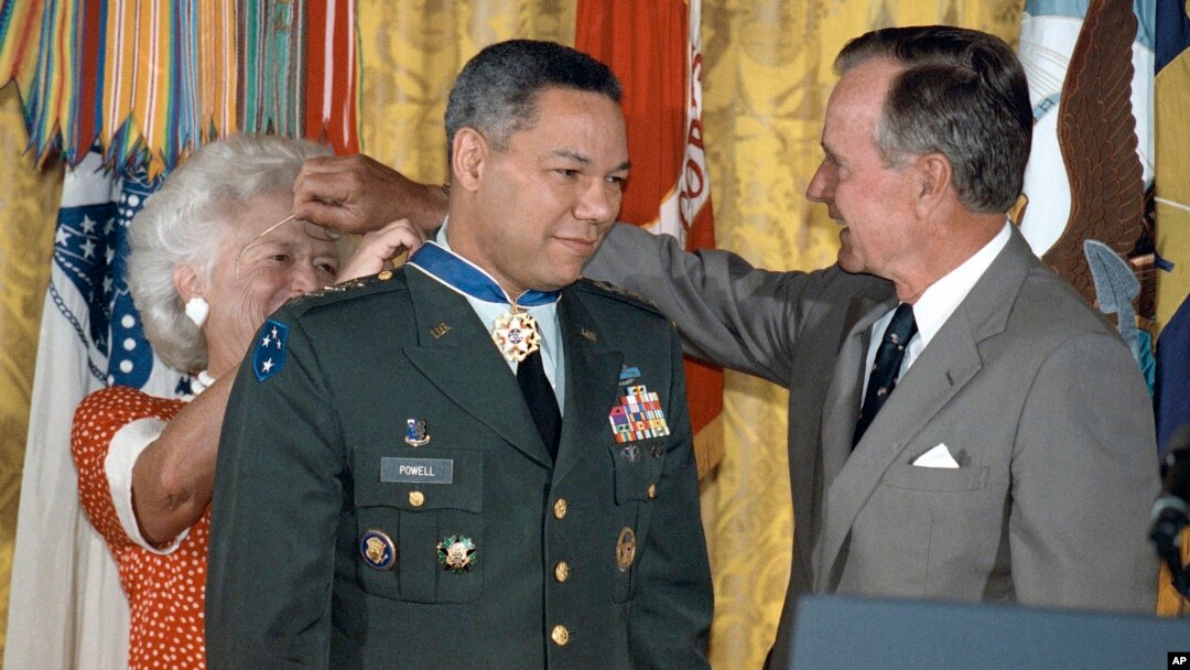 FILE - President George Bush lends his glasses to first lady Barbara Bush as she pins a Medal of Freedom on Gen. Colin Powell, chairman of the Joint Chiefs of Staff, during a White House ceremony, July 3, 1991. 