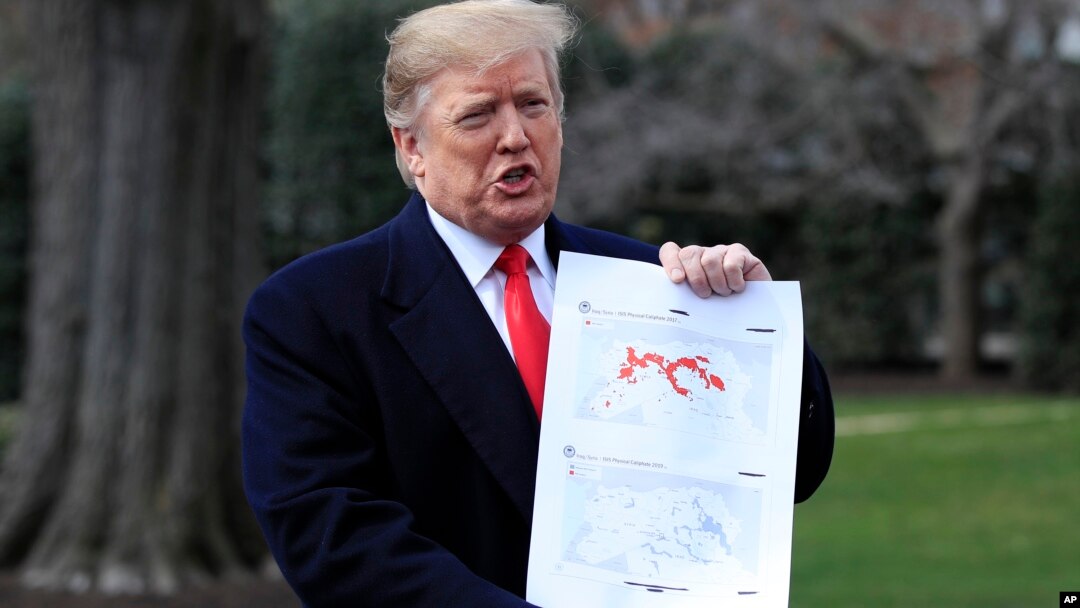 President Donald Trump shows a map of Syria and Iraq showing the presence of the Islamic State in 2017 and 2019, as he speaks to reporters before leaving the White House in Washington, March 20, 2019.