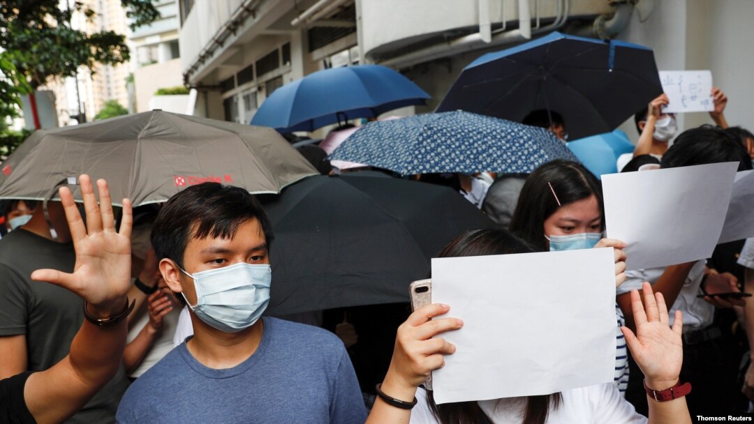 Supporters raise white paper to avoid slogans banned under the national security law as they support arrested anti-law protester outside Eastern court in Hong Kong