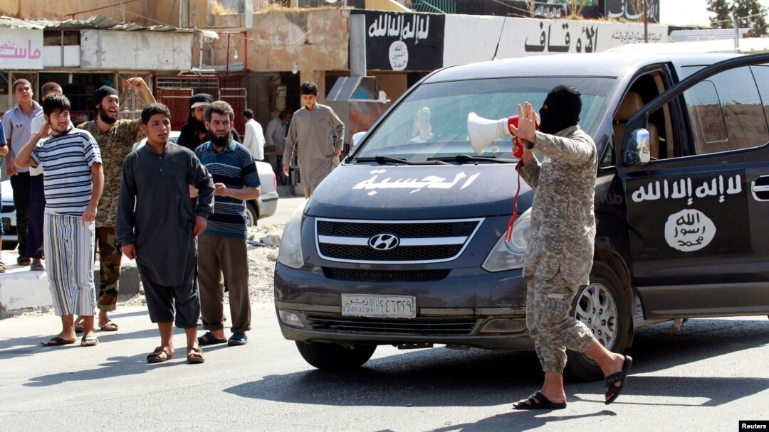 An Islamic State militant uses a loud-hailer to announce to residents of Tabqa city that Tabqa air base has fallen to Islamic State militants, in nearby Raqqa city, Syria, Aug. 24, 2014.