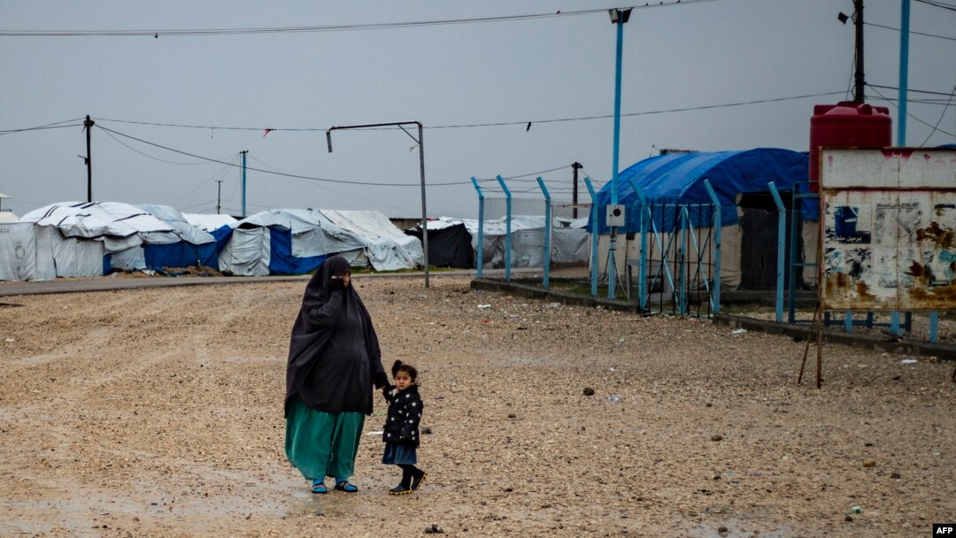 FILE - This file photo taken on March 4, 2021 shows a woman holds a child's hand at Camp Roj in Syria, where relatives of people suspected of belonging to the Islamic State (IS) group are held.