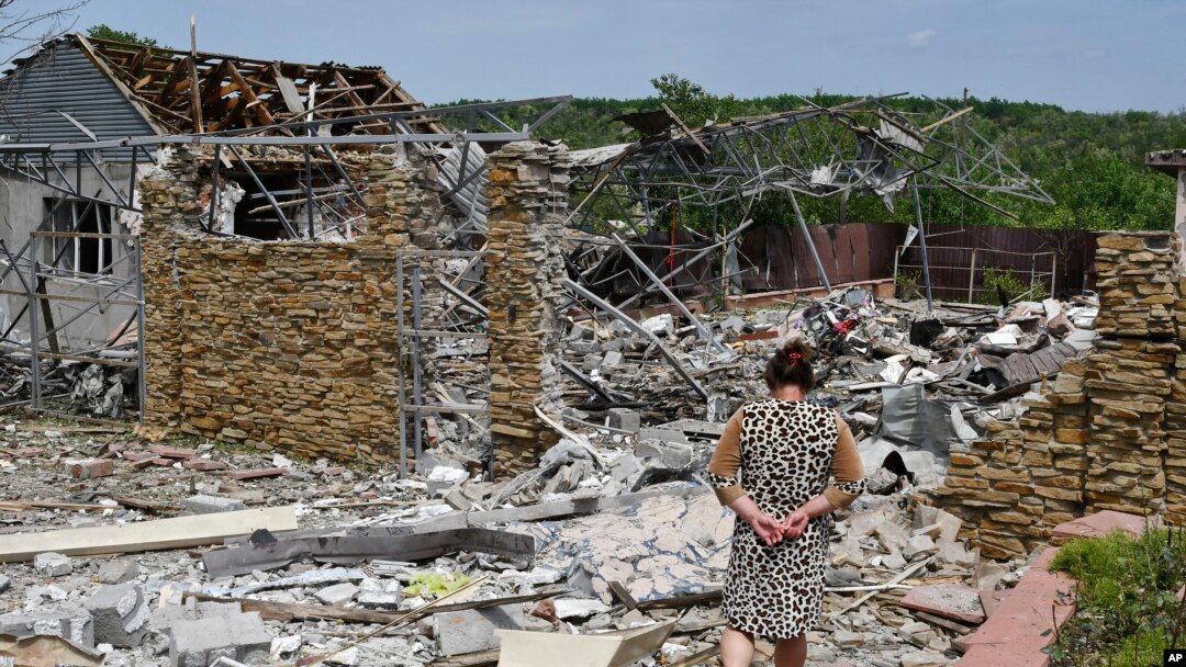 FILE - An elderly woman walks next to a building damaged by an overnight missile strike in Slovyansk, Ukraine, Wednesday, June 1, 2022.