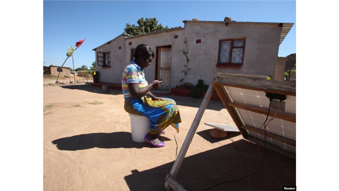 FILE - A women checks a message on her mobile phone in Epworth, east of the capital Harare, Zimbabwe, Aug. 11, 2016.