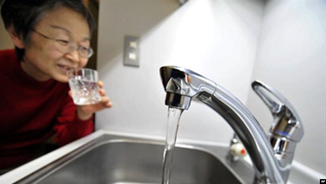 A woman fills a glass with water from a tap in Tokyo on March 23, 2011
