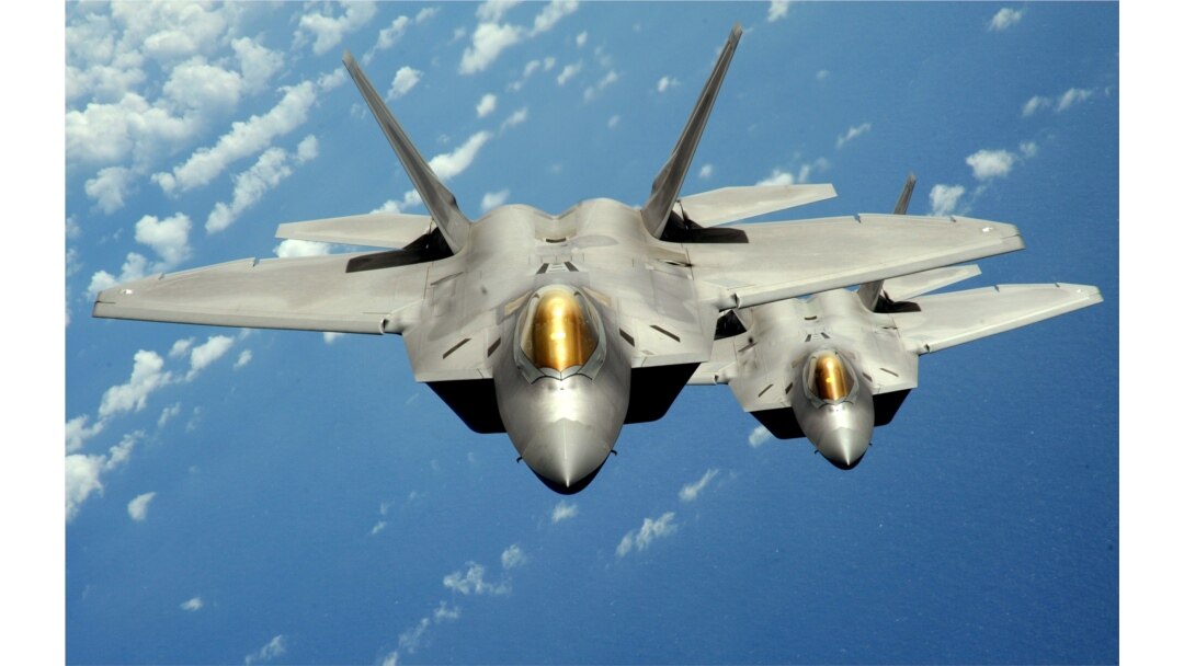 FILE - Two U.S. Air Force F-22 Raptor stealth jet fighters fly near Andersen Air Force Base.